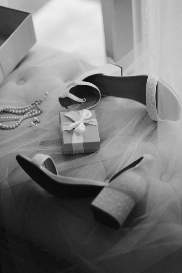 Bridal shoes, pearls and a gift box on a tulle-covered window seat