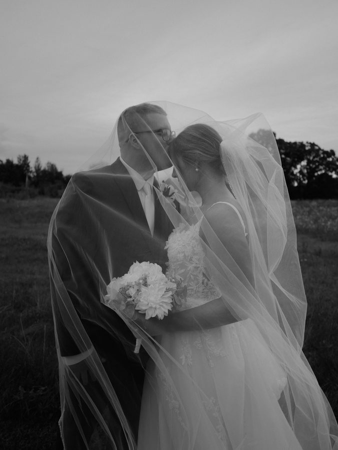 Alyssa and Eric wrapped in her veil, black and white