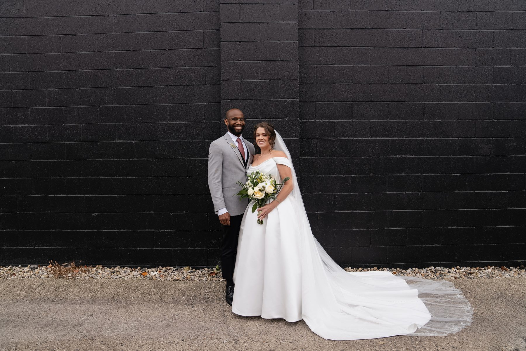 Pary and Edward, full-length portrait against the black brick at Liter House