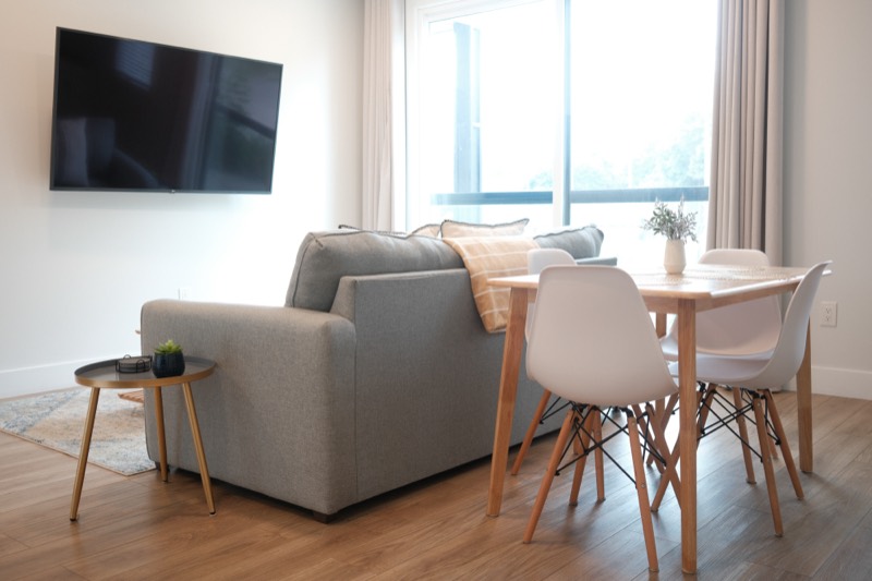 Bright living and dining area with a gray sofa and wood table